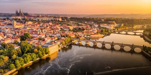 Goldenes Abendlicht legt sich über Prag mit der Moldau, der Karlsbrücke und der Prager Burg über der Altstadt.